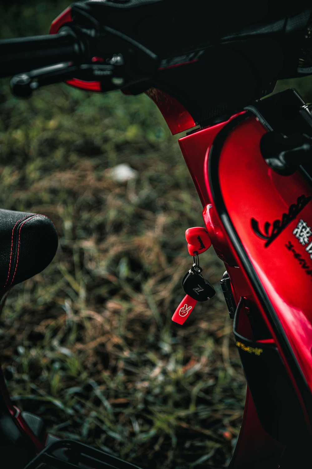 a close up of a red motorcycle parked in a field