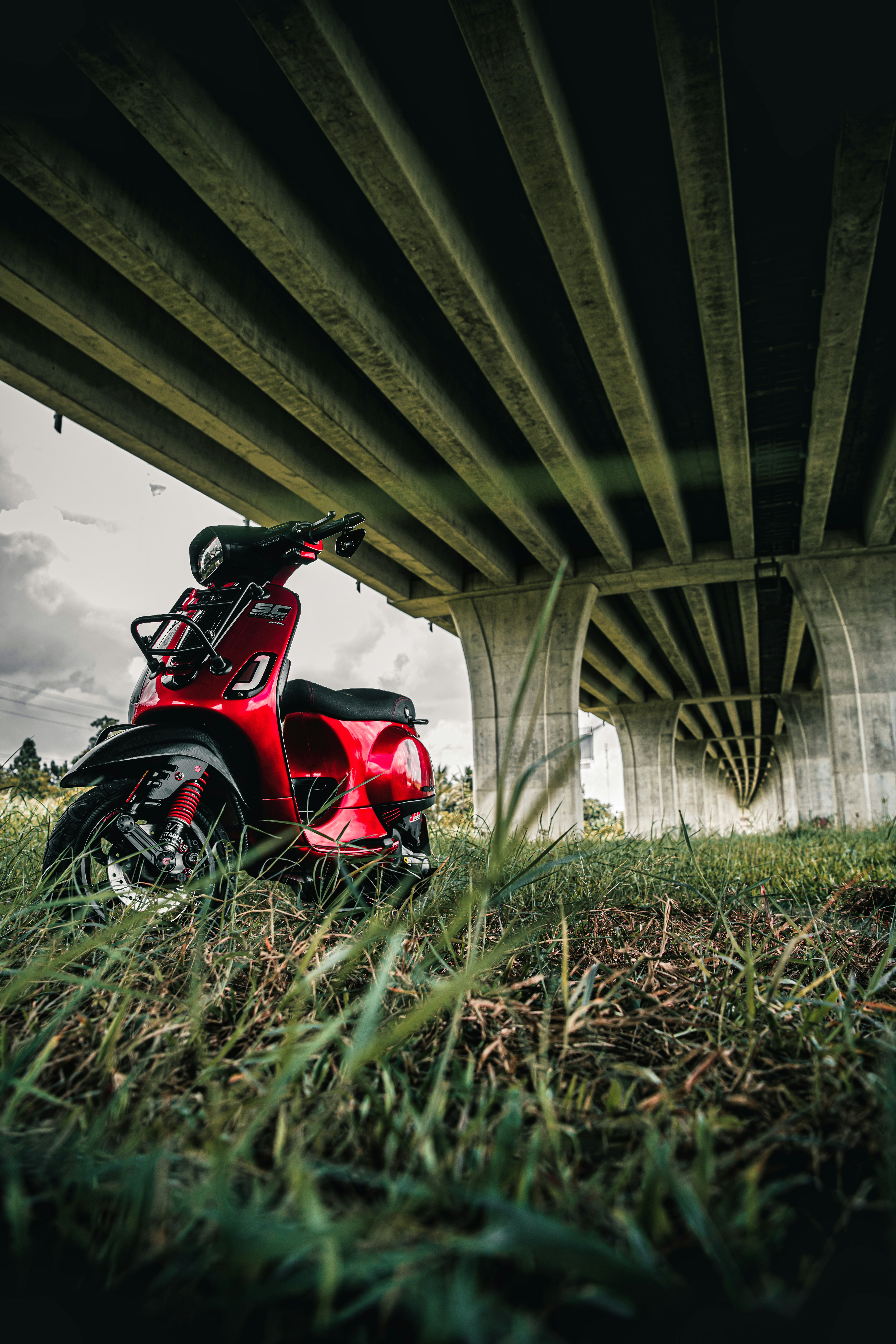 a red scooter is parked under a bridge