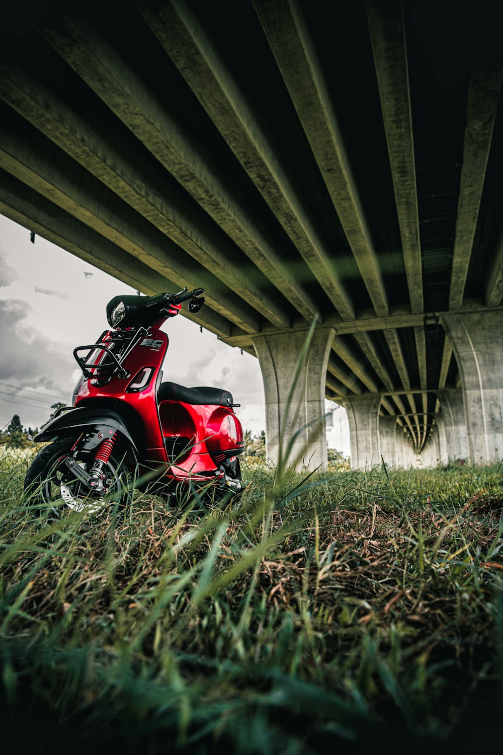 a red scooter is parked under a bridge