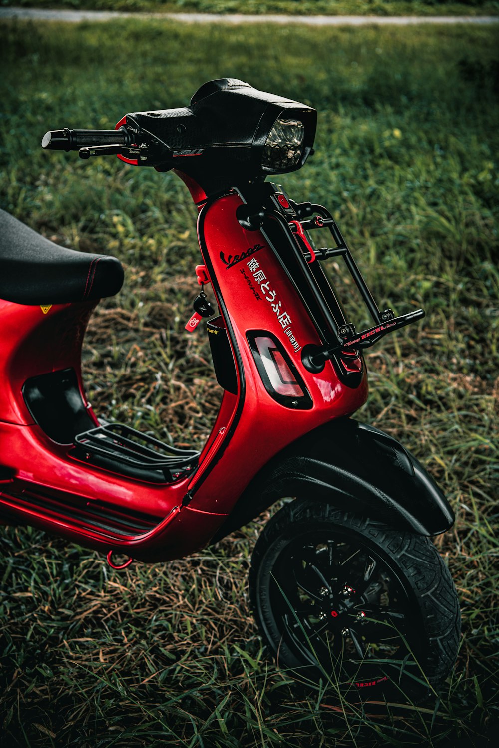 a red scooter is parked in the grass