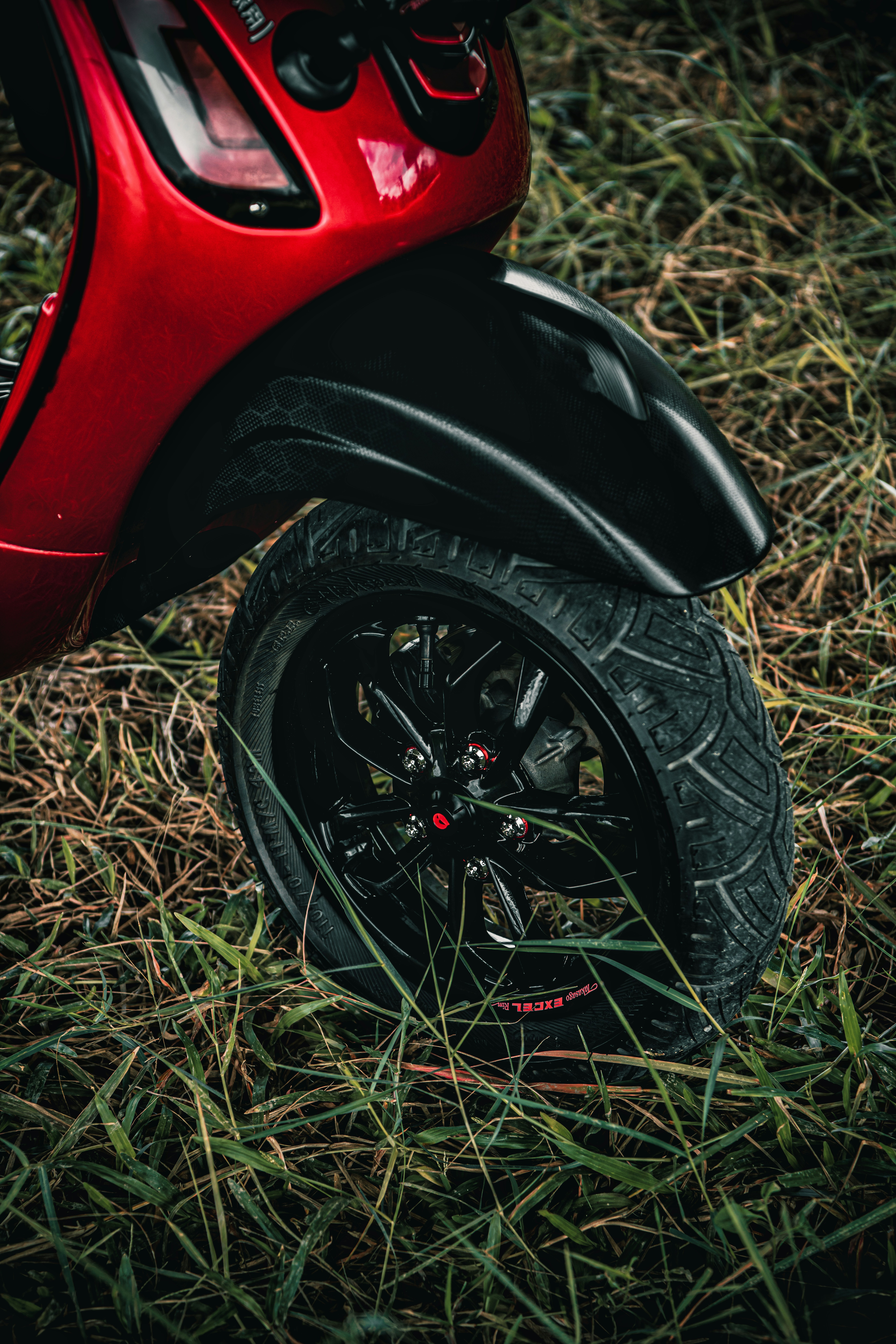 a red scooter is parked in the grass