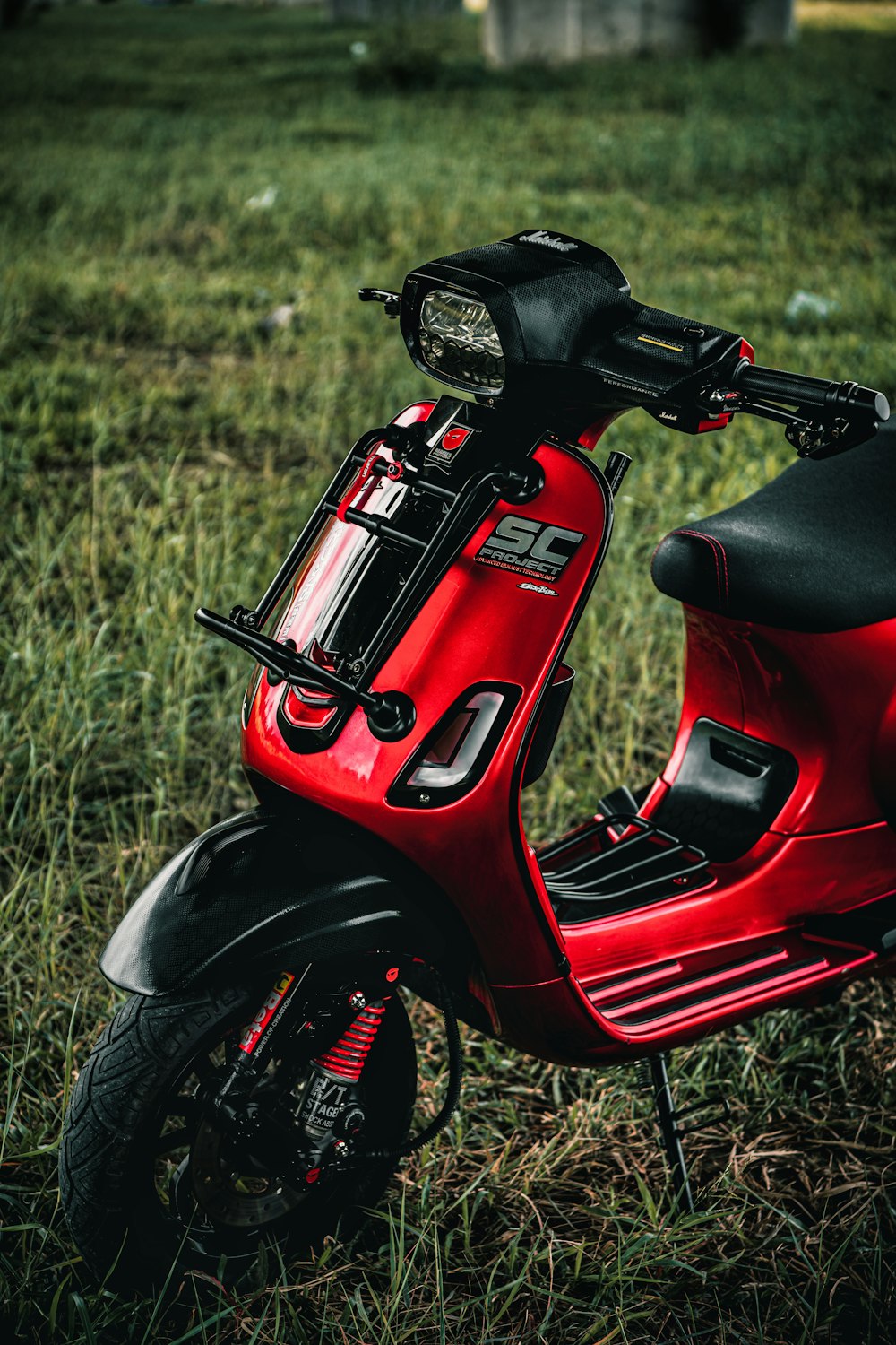 a red scooter parked in a grassy field