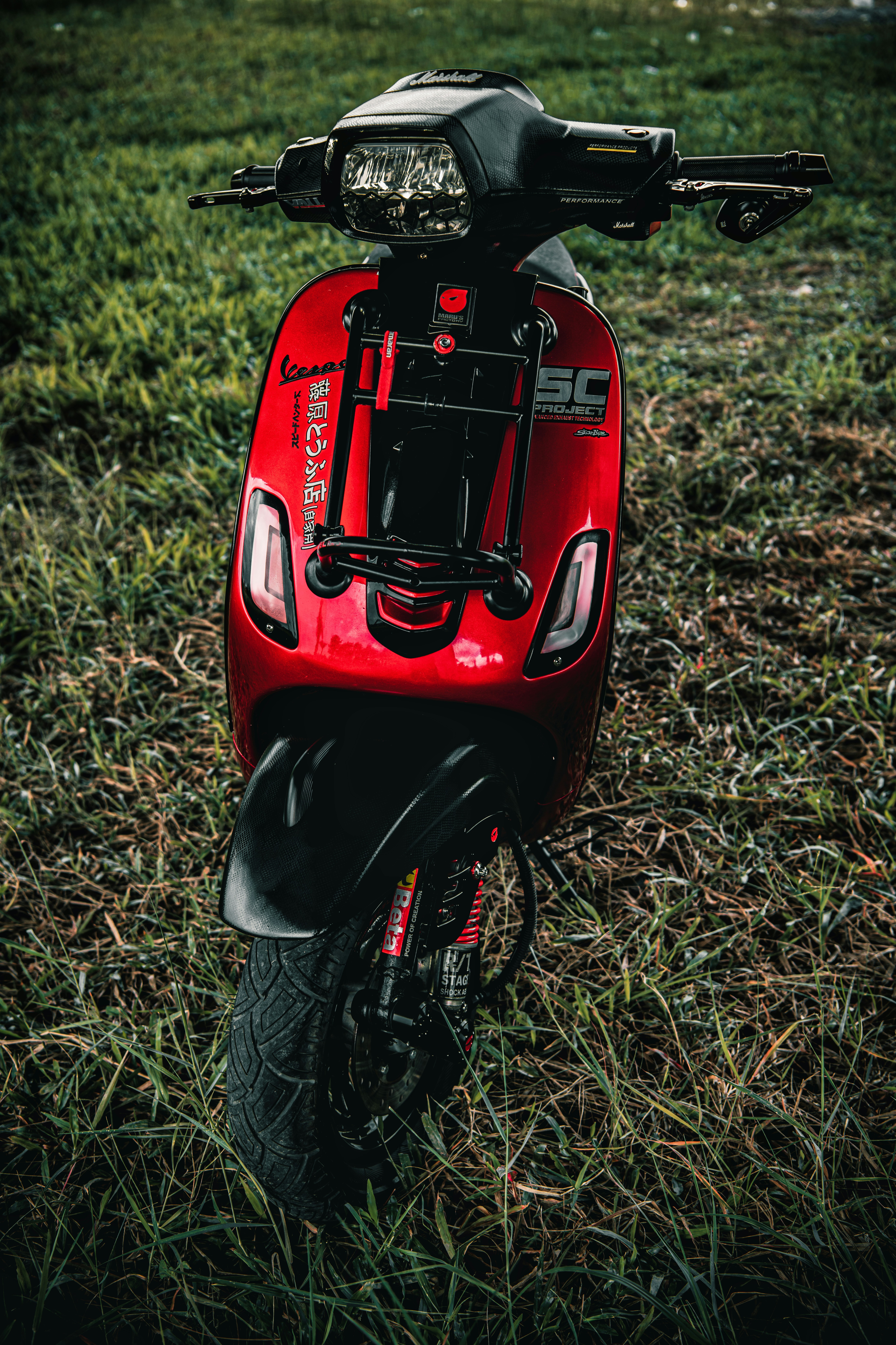a red motorcycle parked on top of a lush green field