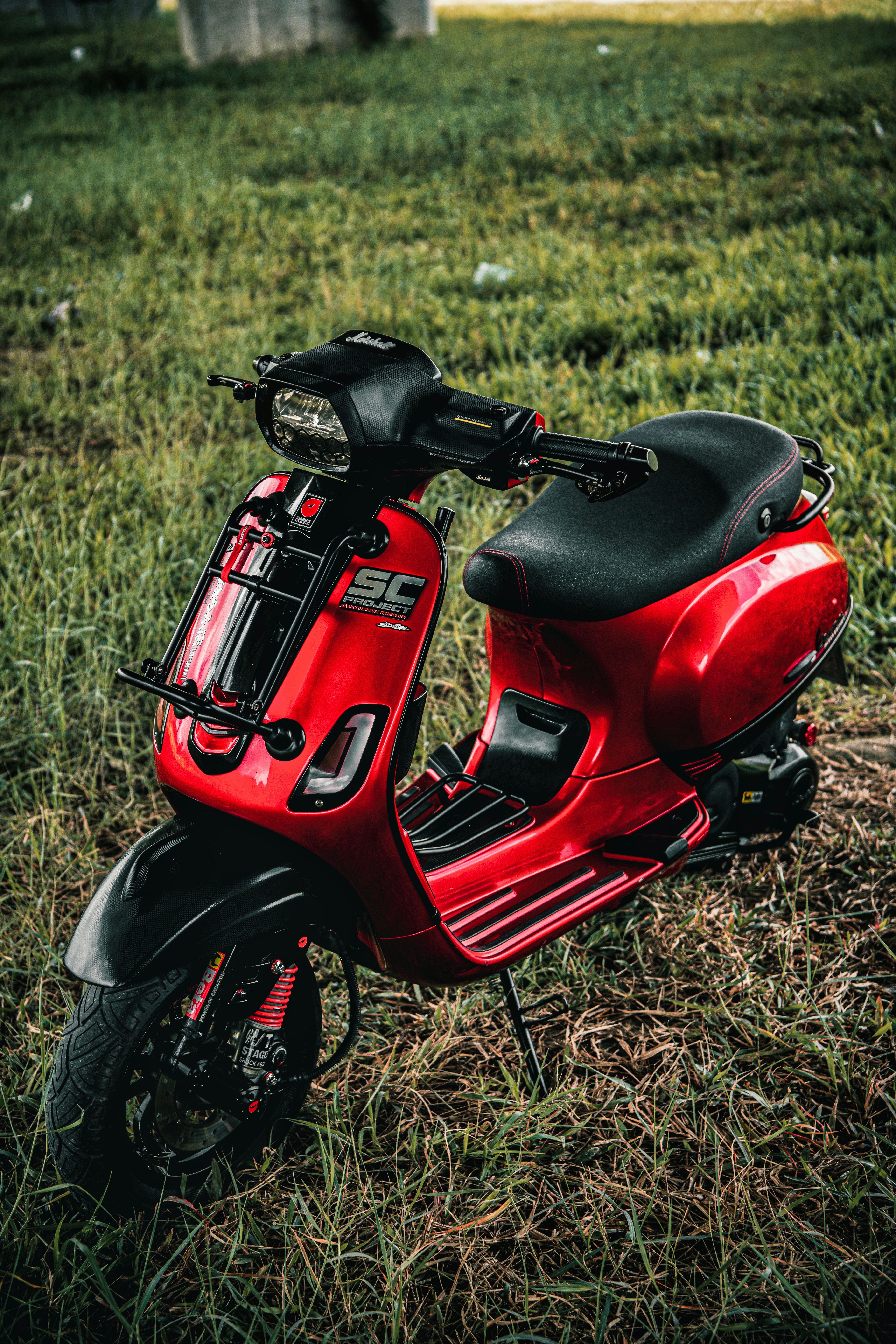 a red scooter is parked in a grassy field
