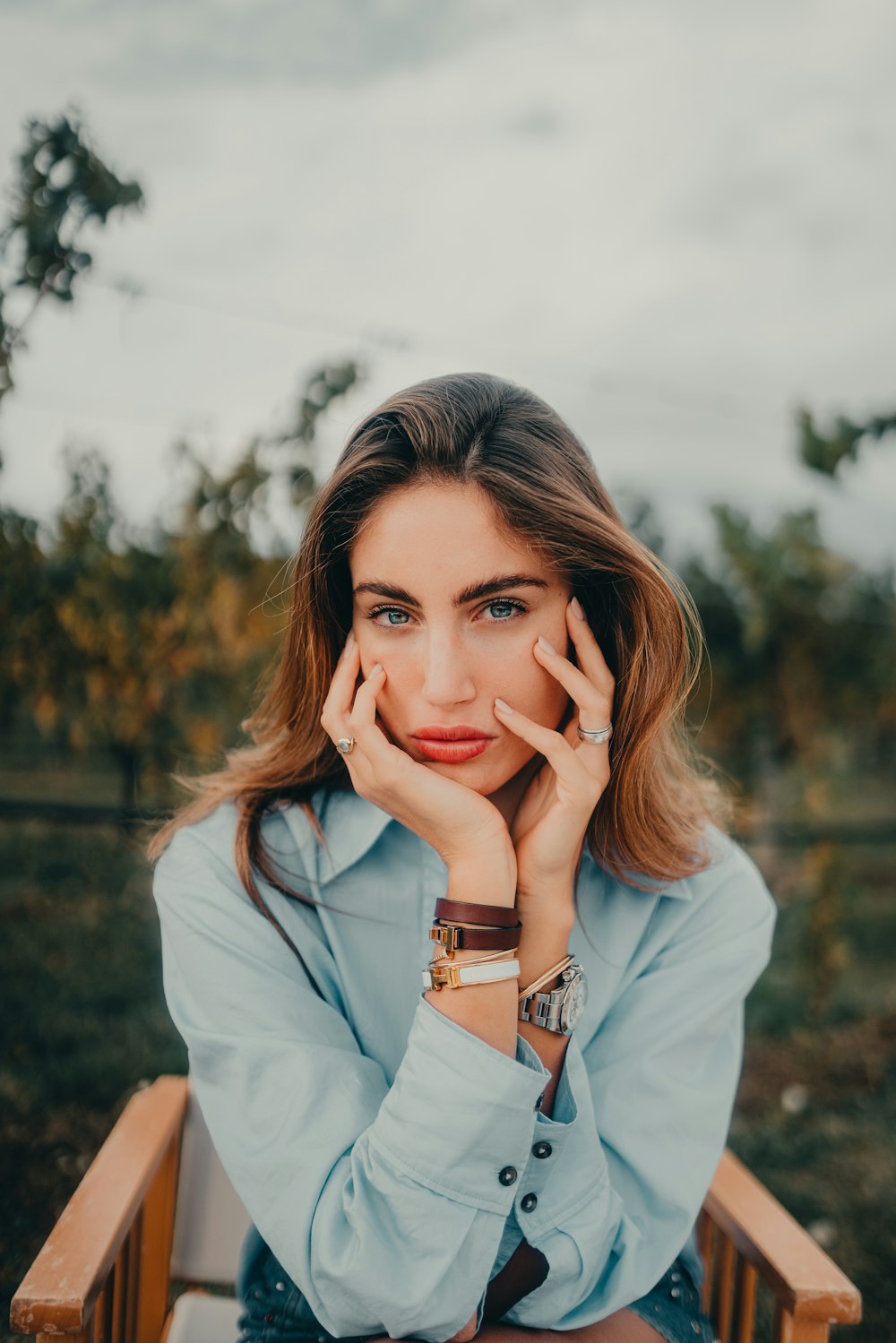 a woman sitting in a chair with her hands on her face