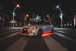 A car illuminated with colorful underglow lights at night.