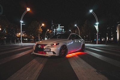 A car illuminated with colorful underglow lights at night.