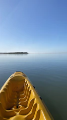 A bright yellow kayak floating gently on calm turquoise water under a sunny sky.
