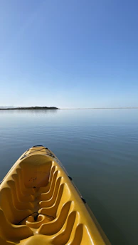 A bright yellow kayak floating gently on calm turquoise water under a sunny sky.