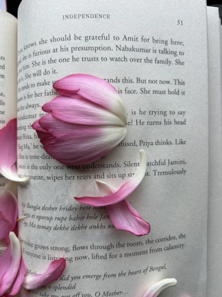 Close-up of a teen girl reading a pink-covered book surrounded by delicate flowers