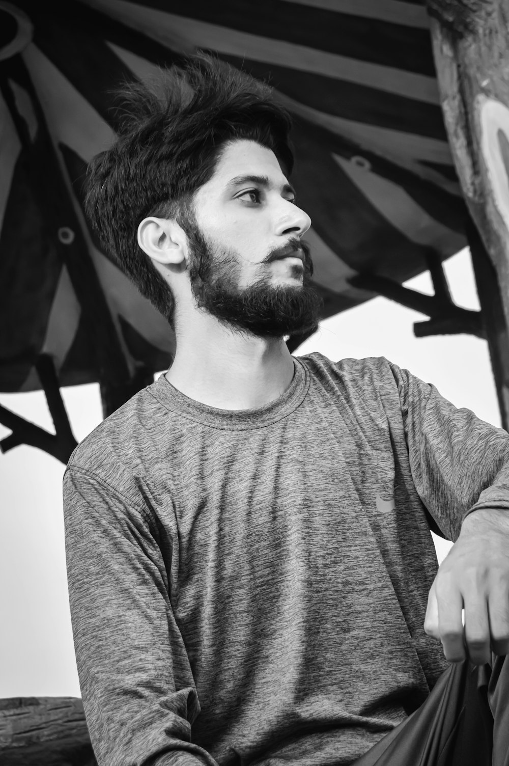 a man with a beard sitting under an umbrella