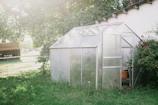 A sturdy polycarbonate greenhouse standing tall in a suburban backyard.