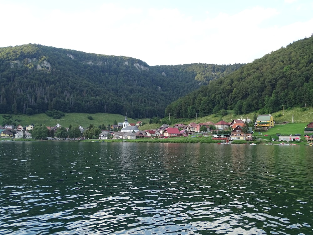 a lake with houses and mountains in the background