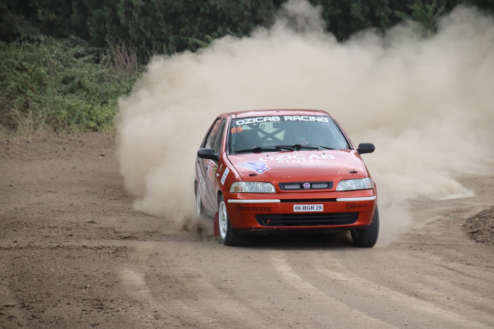 a red car driving down a dirt road