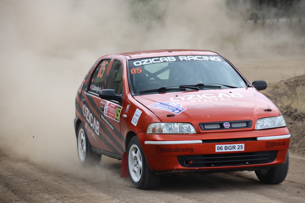 a red car driving down a dirt road