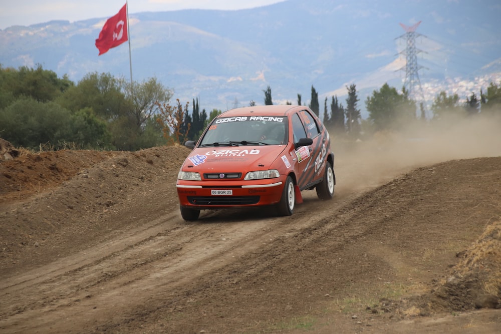 a red car driving down a dirt road