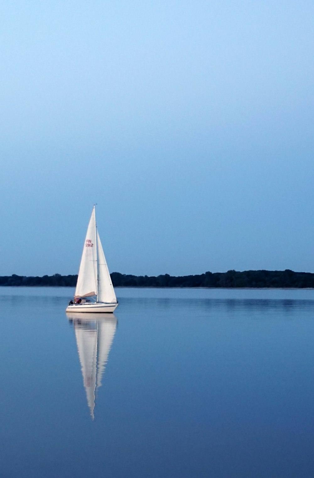 Una barca a vela naviga su un lago calmo