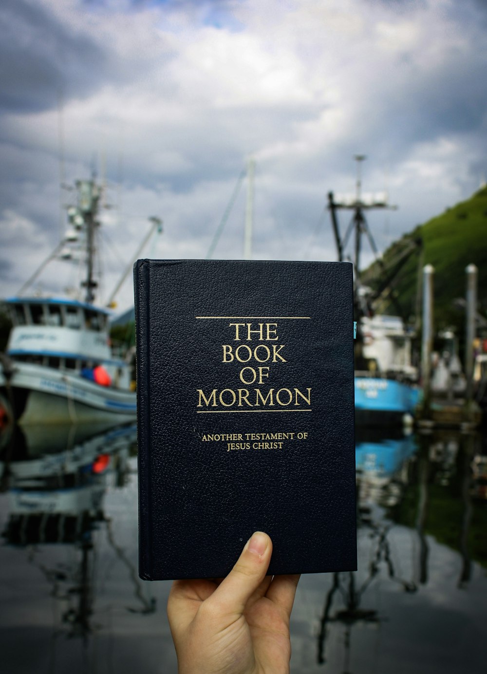 a person holding up a book in front of boats