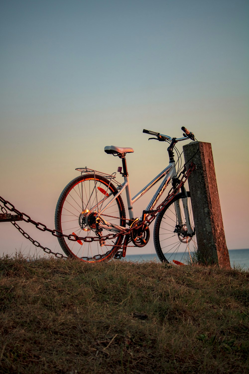 uma bicicleta acorrentada a um poste de madeira em uma colina