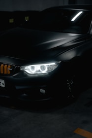A set of sleek car headlights glowing softly in a dim garage.