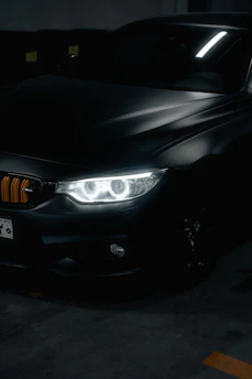 A sleek black car shining under soft garage lighting with blue and gold accents.