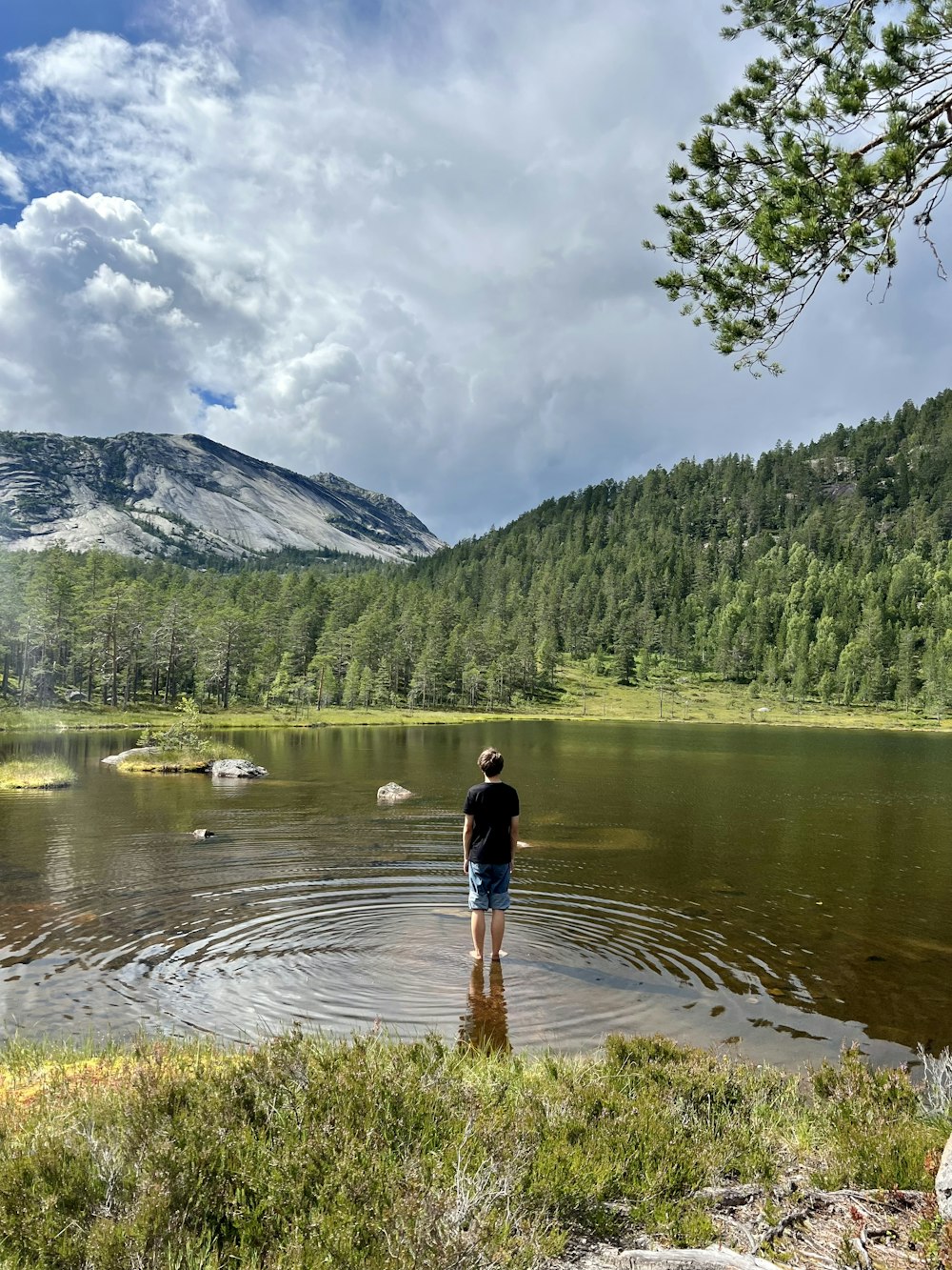 a person standing in a lake with mountains in the background