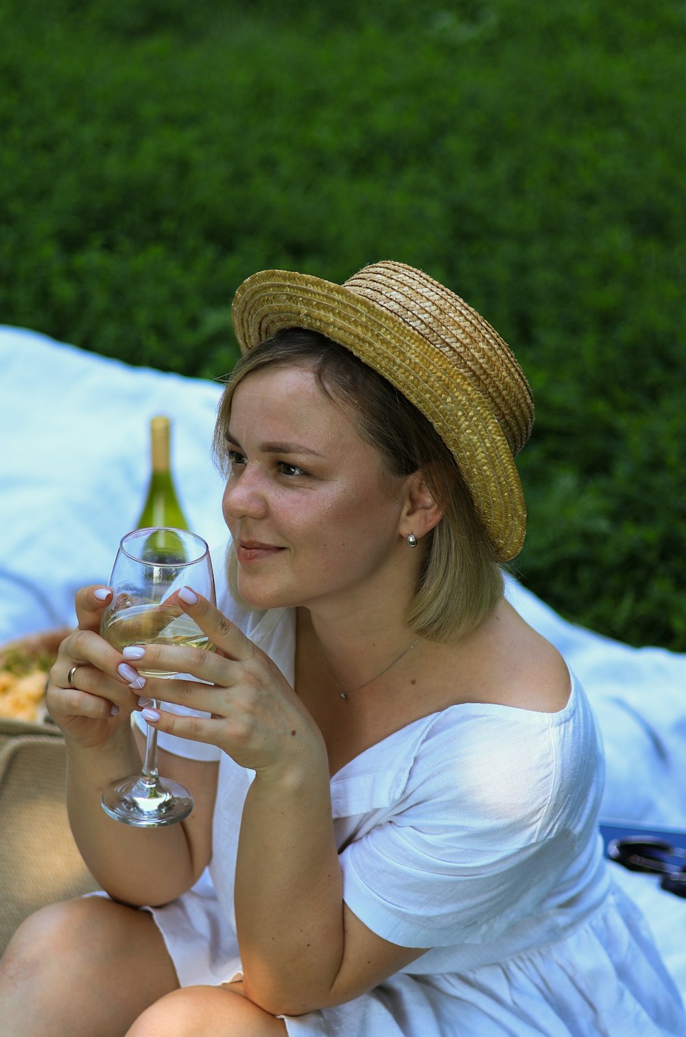 eine frau, die auf einer decke sitzt und ein glas wein hält