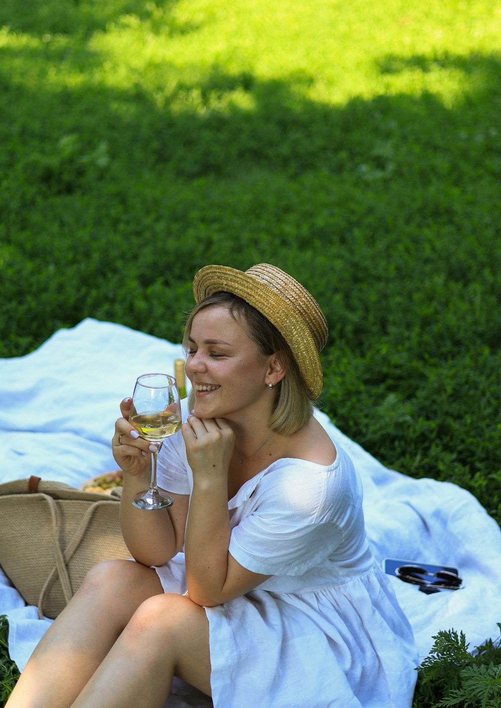 a woman sitting on a blanket holding a glass of wine