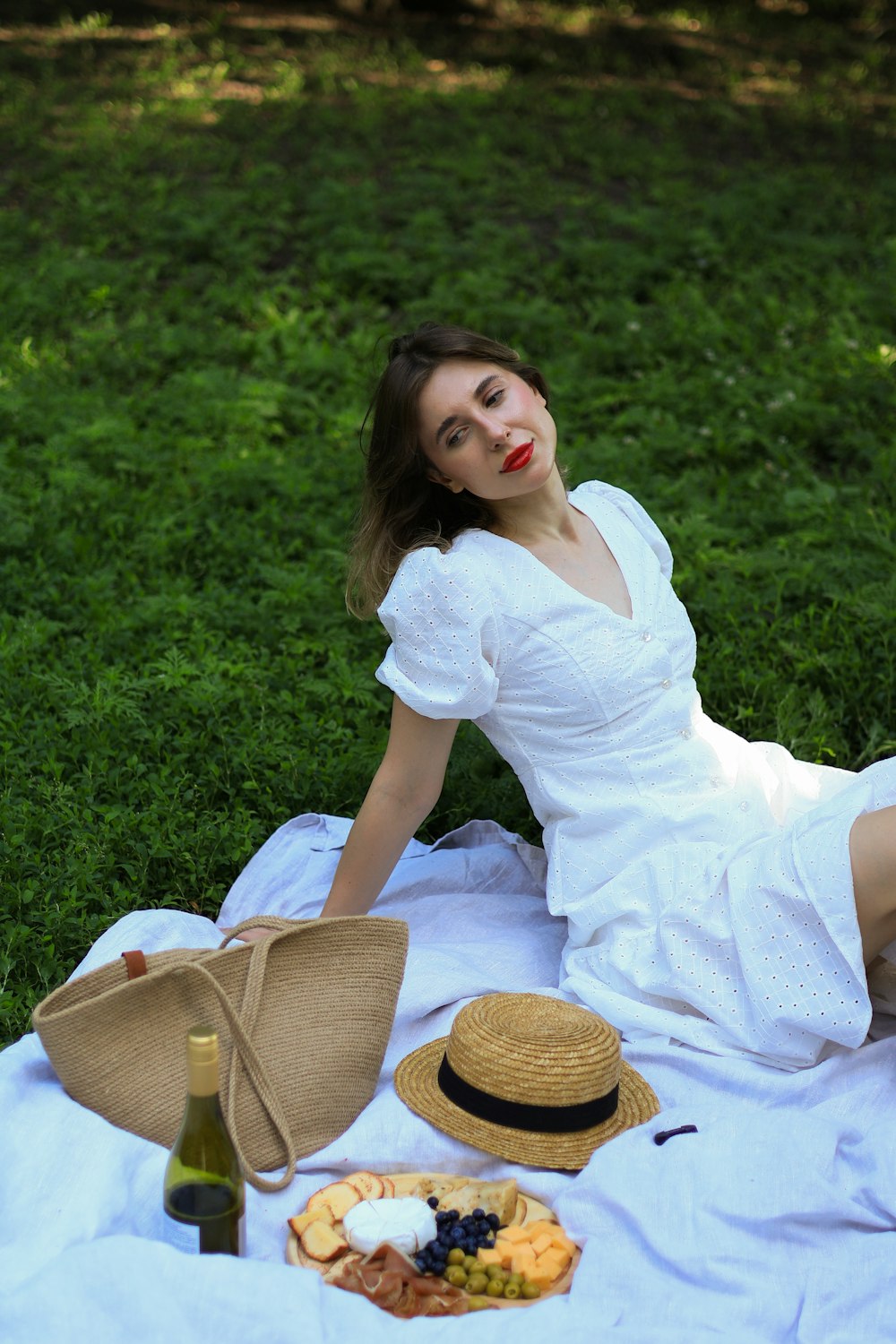 a woman in a white dress sitting on a blanket