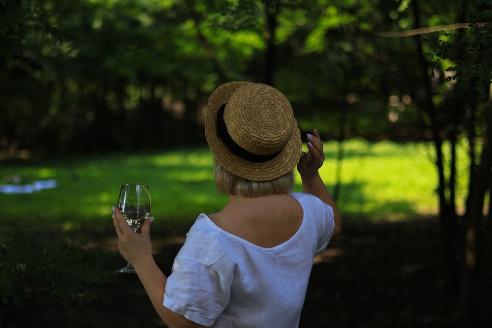 eine Frau mit Hut, die ein Glas Wein hält