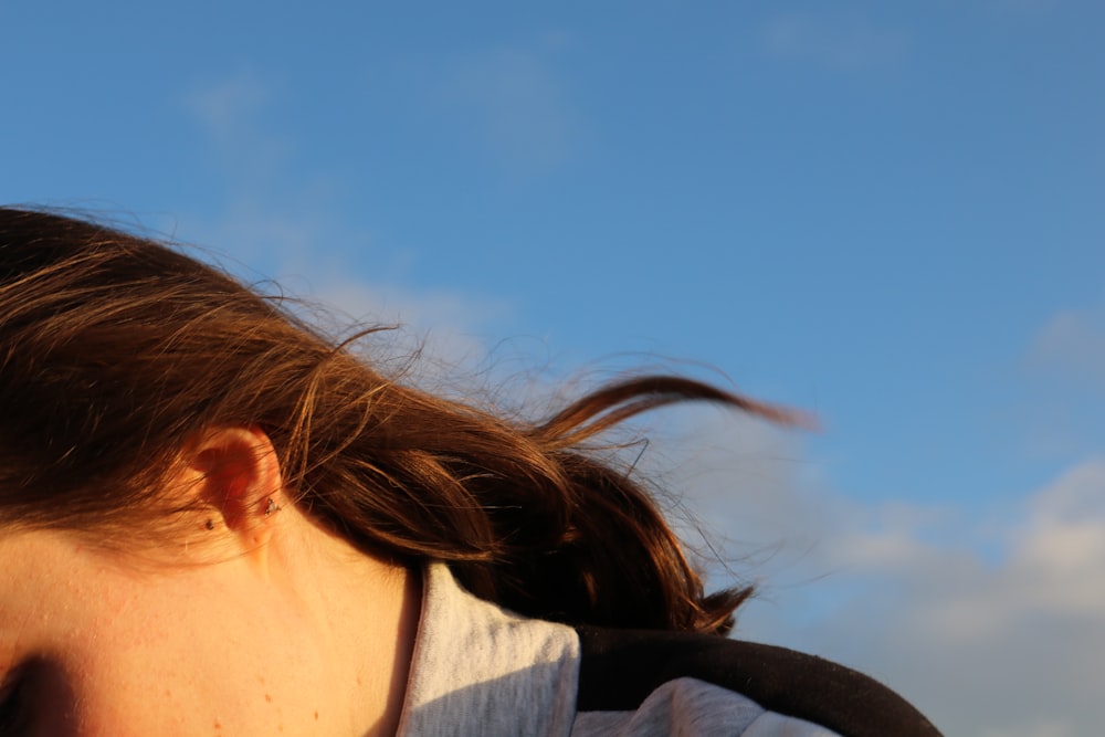 a close up of a woman's face with a blue sky in the background