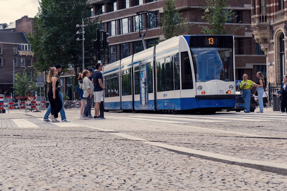 a blue and white tram on a city street