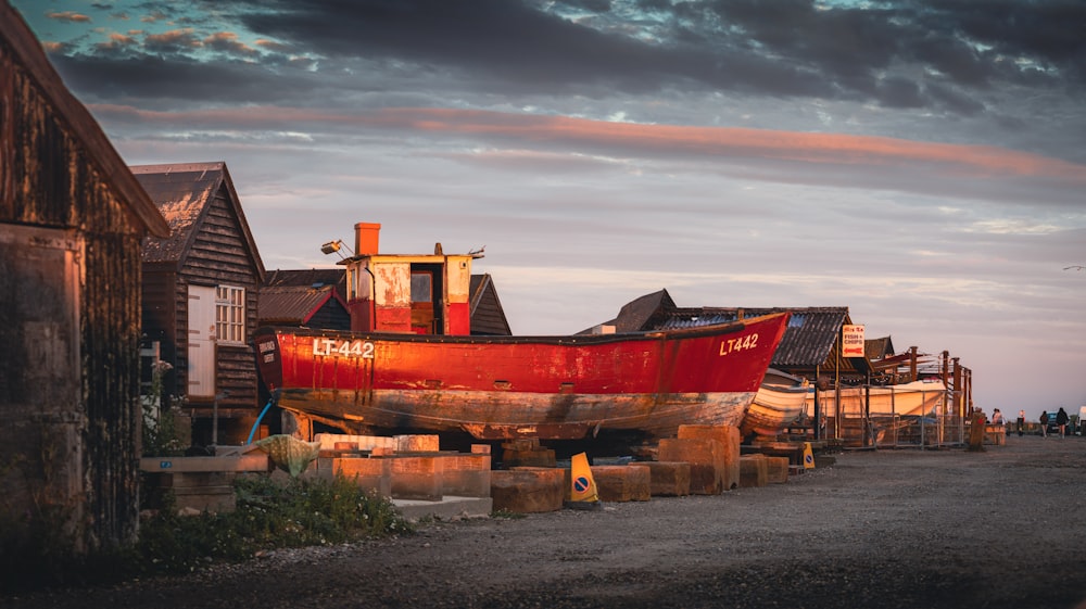 a red boat sitting on top of a wooden dock