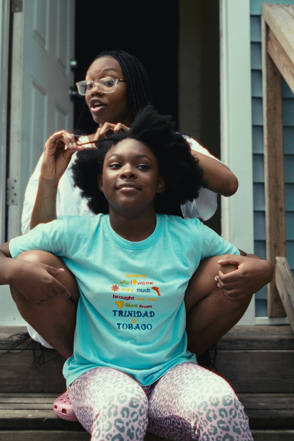 two women sitting on the steps of a house