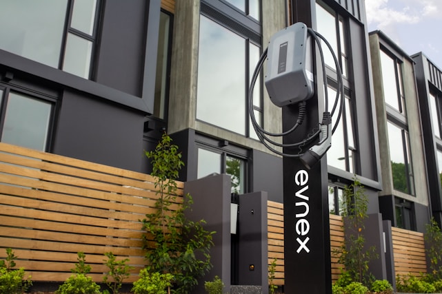 A modern electric vehicle charging station surrounded by greenery.
