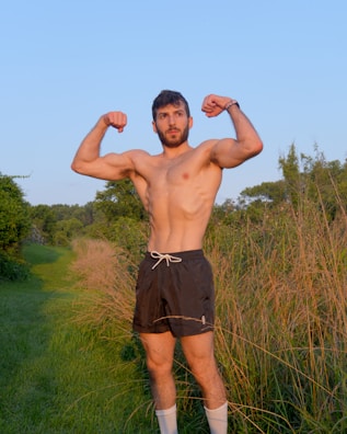 a man standing in a field flexing his muscles