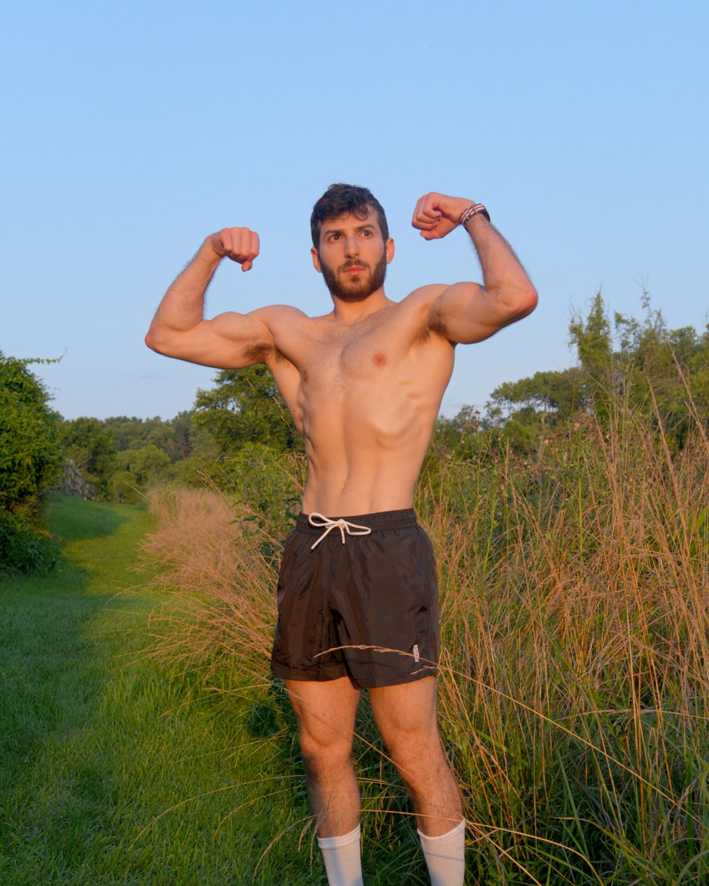 a man standing in a field flexing his muscles