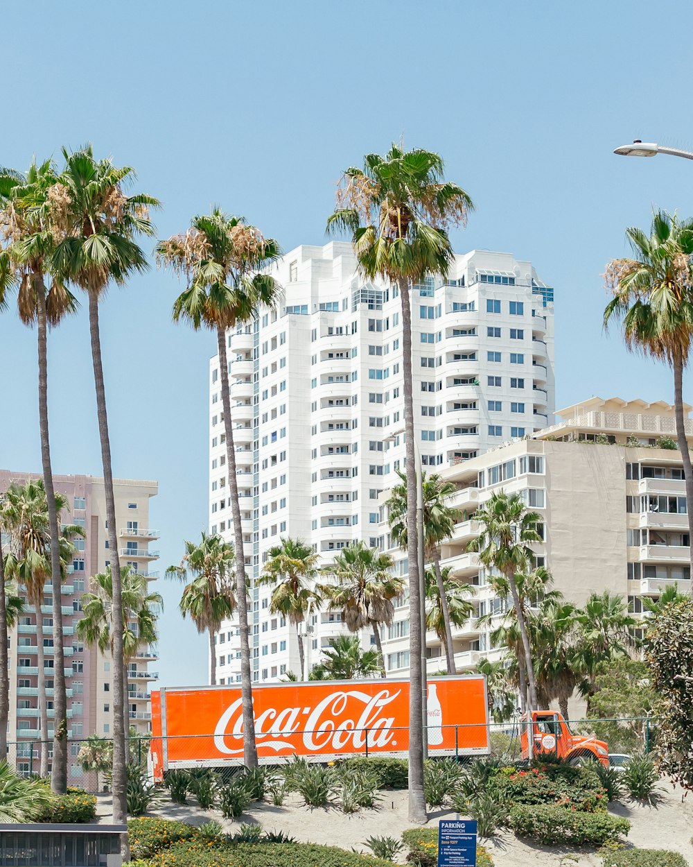 a coca - cola sign in front of palm trees and buildings