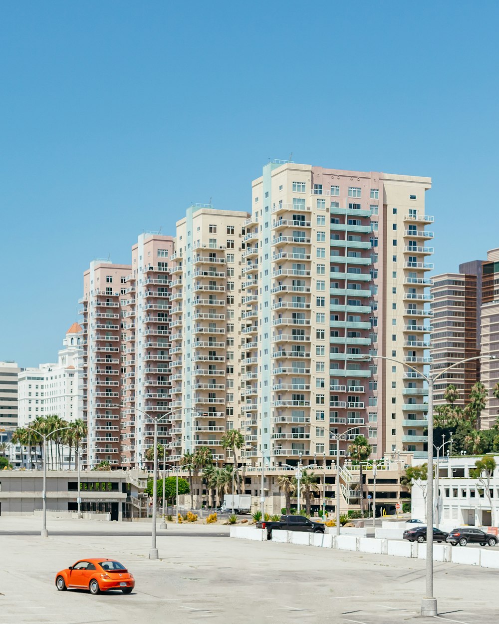 an orange car parked in a parking lot next to tall buildings