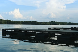 A quiet lakeside with a small wooden dock and calm water reflecting the sky