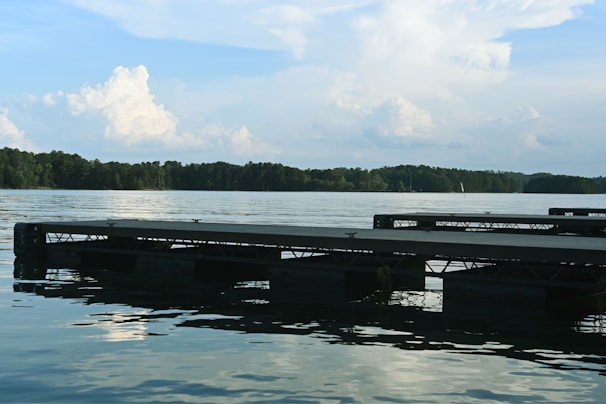 A quiet lakeside with a small wooden dock and calm water reflecting the sky