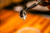 An artistic shot of slime dripping slowly off a spoon against a soft background.