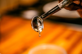 A close-up of golden syrup dripping from a spoon against a neutral background.