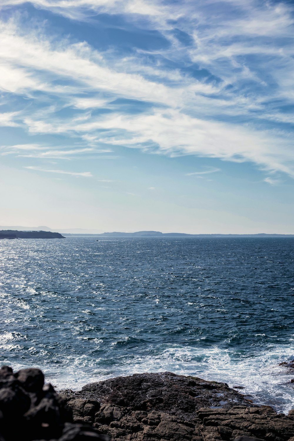 a large body of water sitting next to a rocky shore