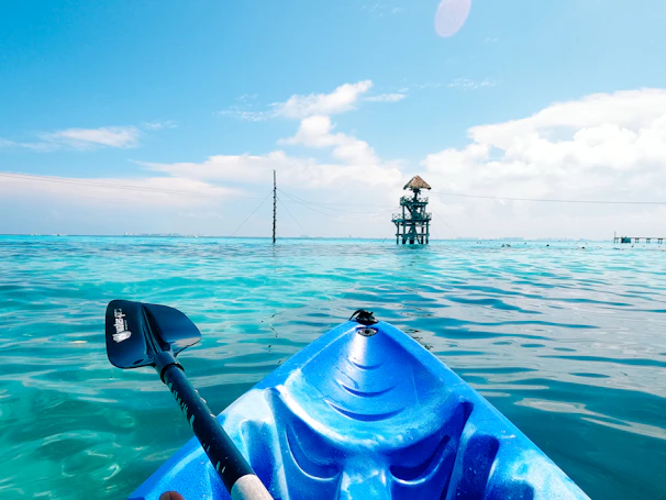 Transparent kayak gliding over the turquoise lagoon waters under a bright blue sky.