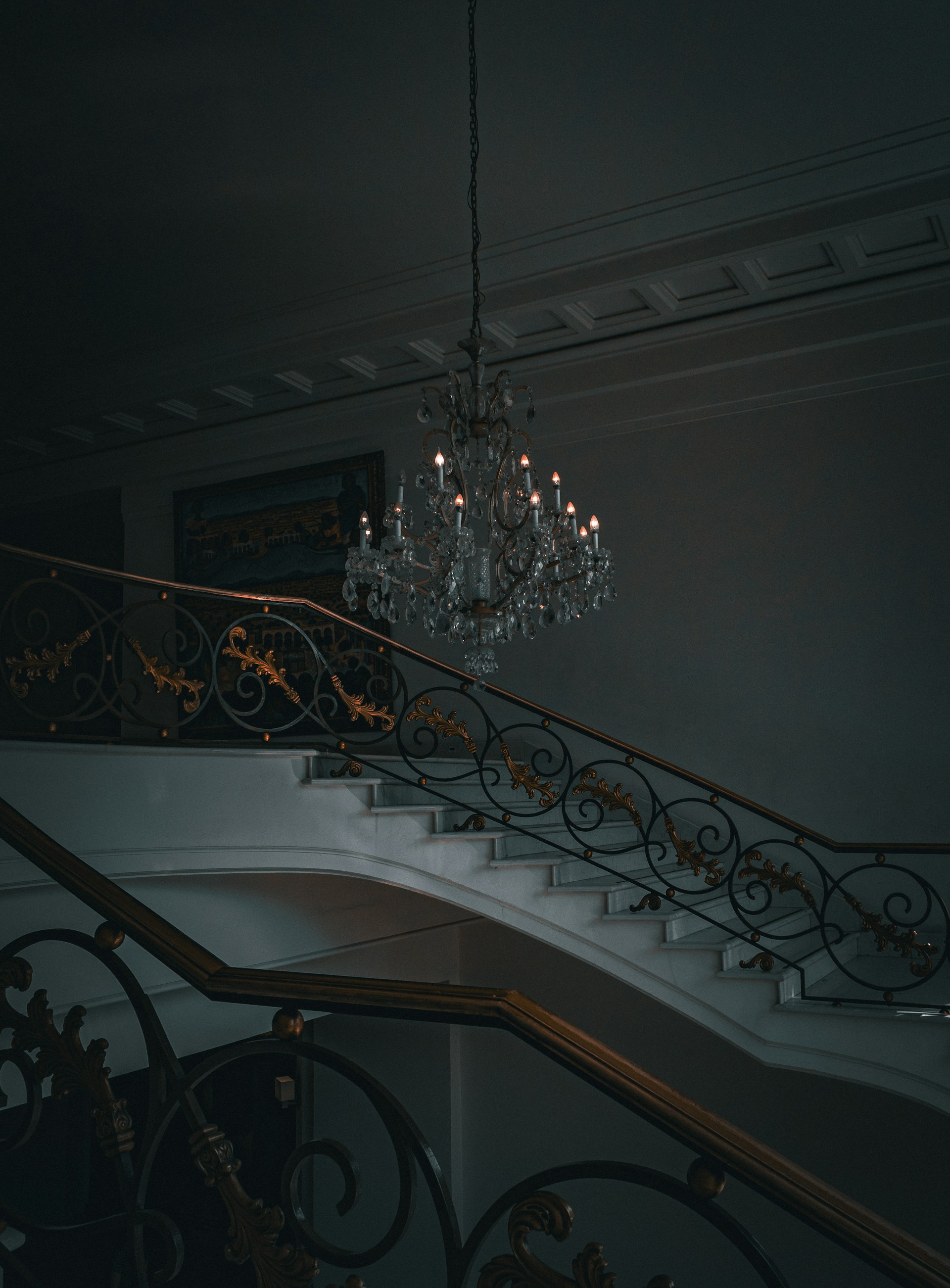 a chandelier hanging from the ceiling next to a set of stairs