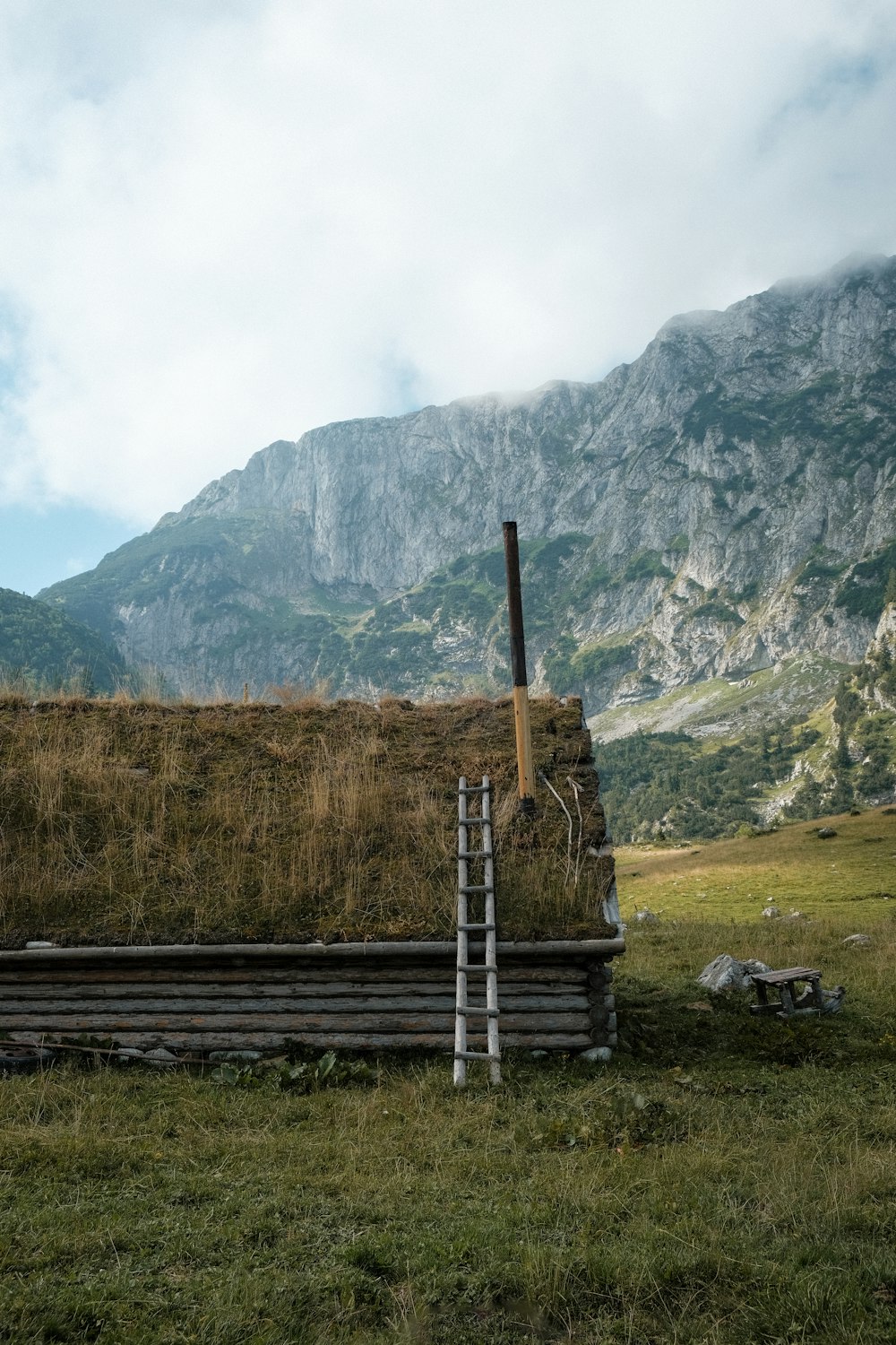 a wooden bench sitting in a grass covered field