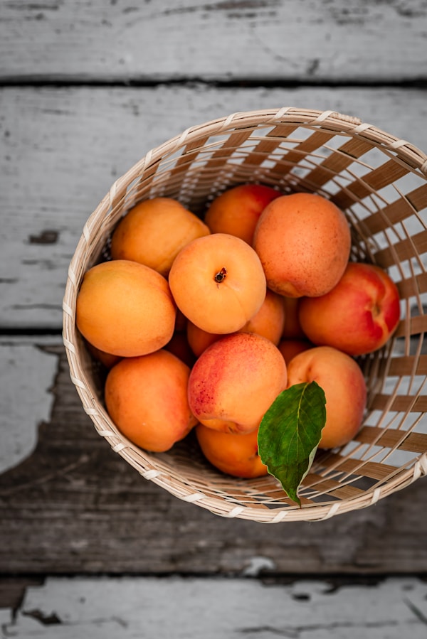 A basket filled with lots of ripe peaches