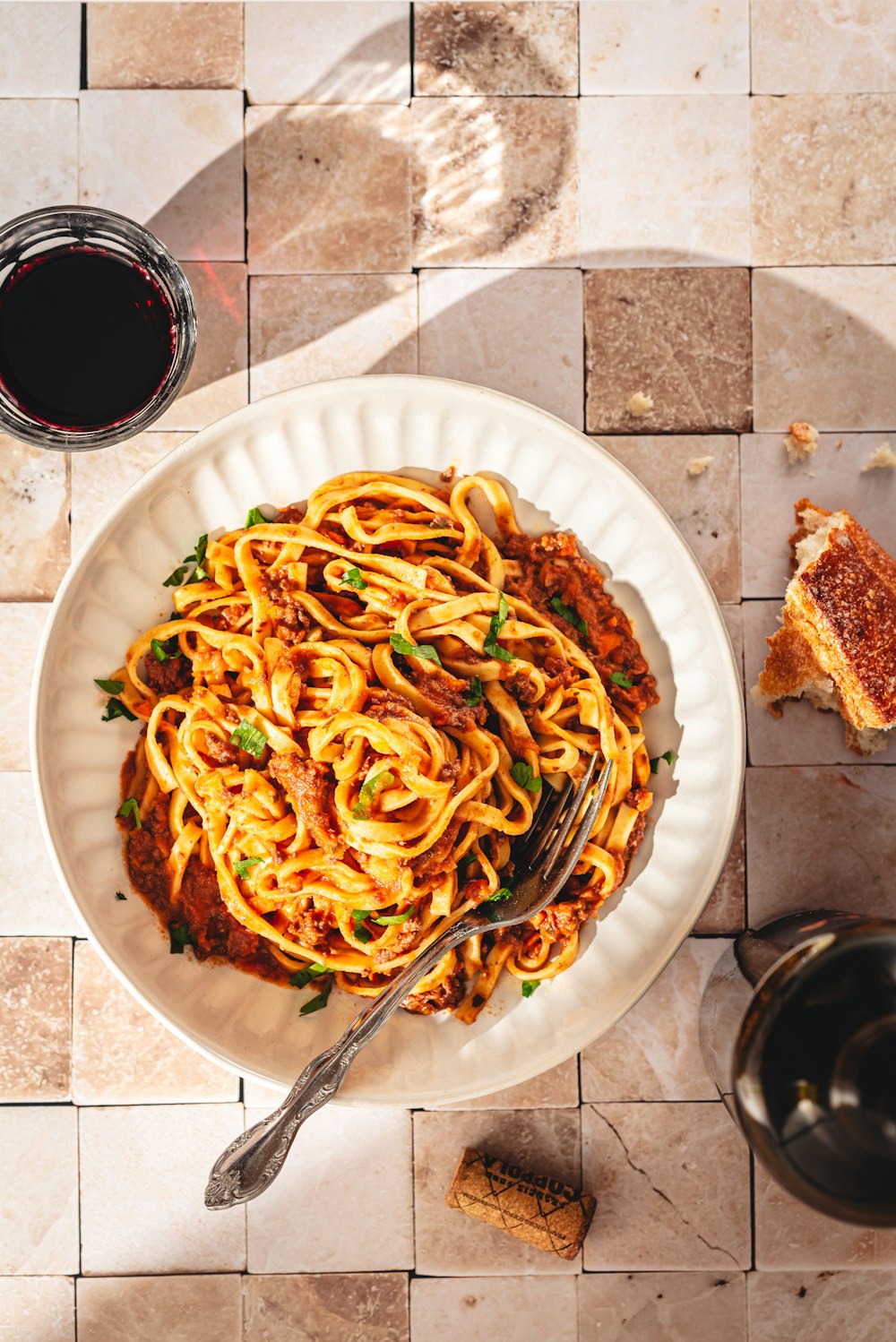 a plate of spaghetti with sauce and bread on a table