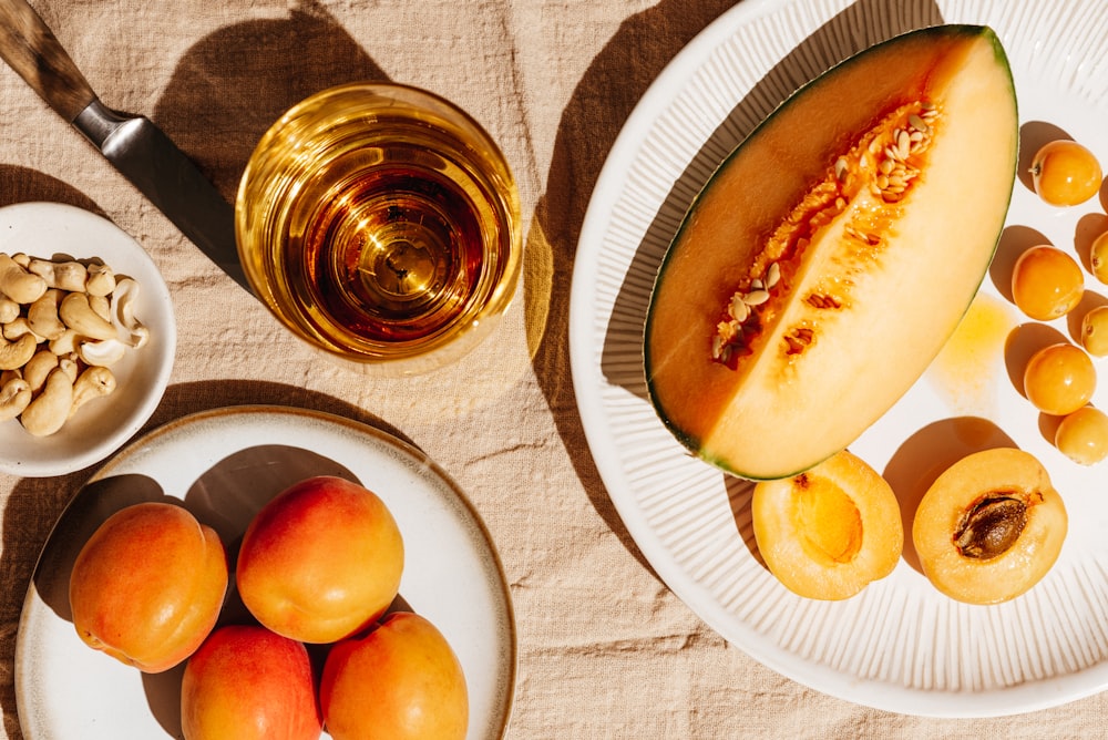 a table topped with plates of fruit and a bowl of nuts